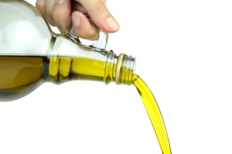 Pouring extra virgin olive oil from glass bottle.